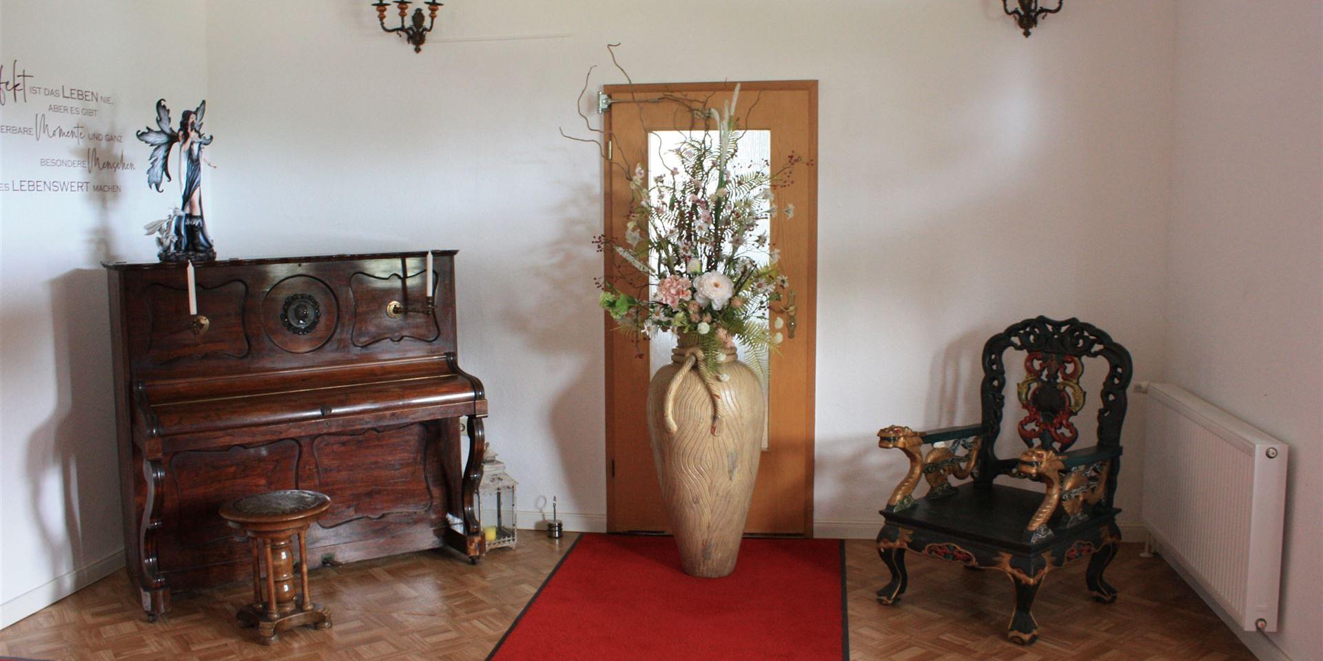 altes Klavier, große Vase und alter Stuhl als Dekoelemente
